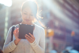 An asian travel nurse uses tech on her tablet.