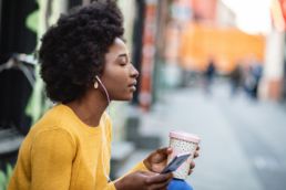 woman listening to podcast with coffee in hand
