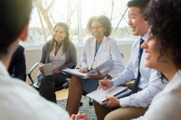Group of healthcare leadership sitting in a circle smiling