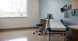 An empty, ready outpatient exam room in soft daylight, representing advanced practice capacity built ahead of demand.