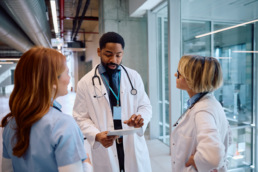 Doctor using touchpad during a meeting with female colleagues in a hospital